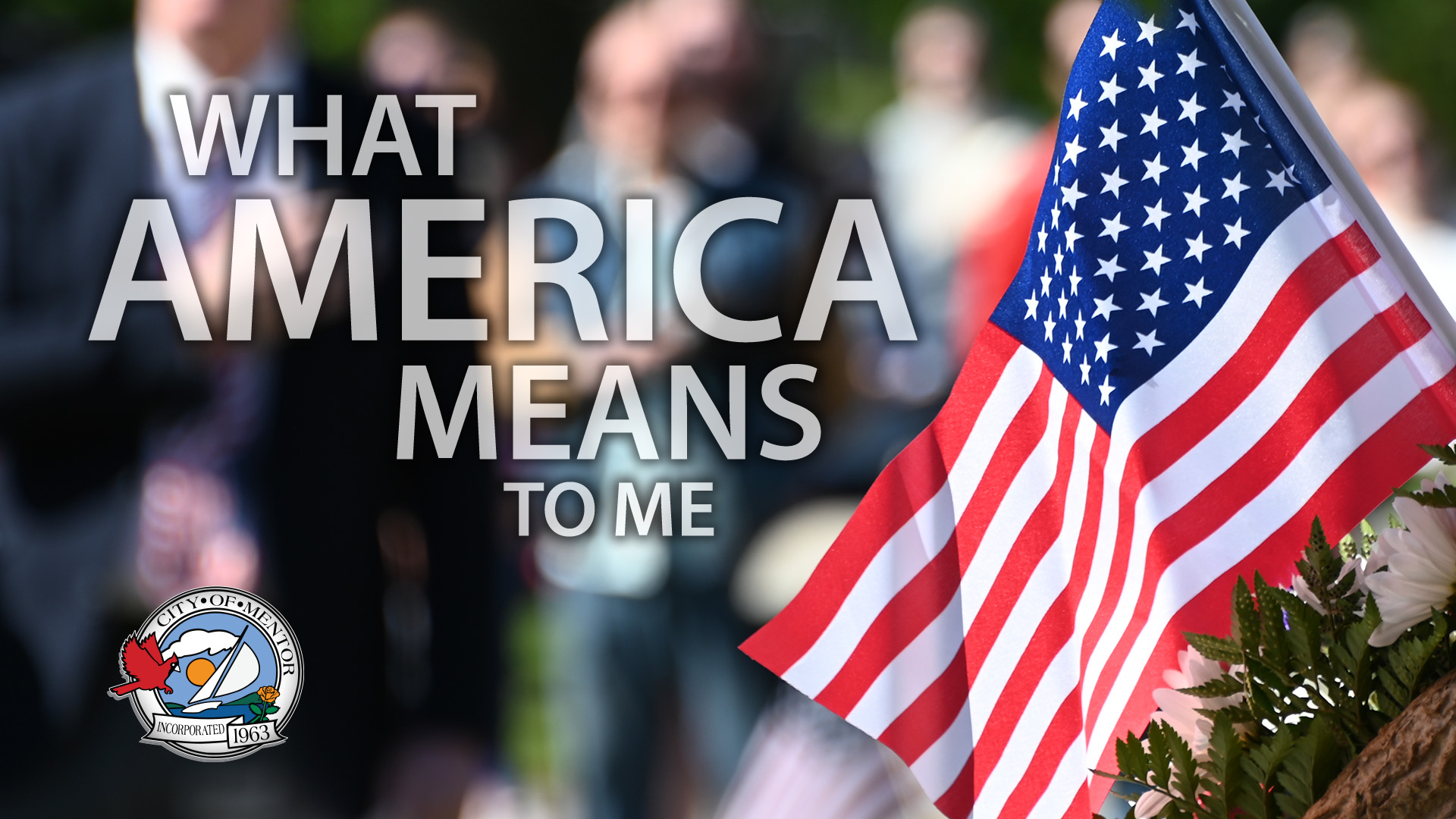 The words "What America Means to Me" overlayed on an image of an American flag with people soft focused in the background with hands over their hearts.